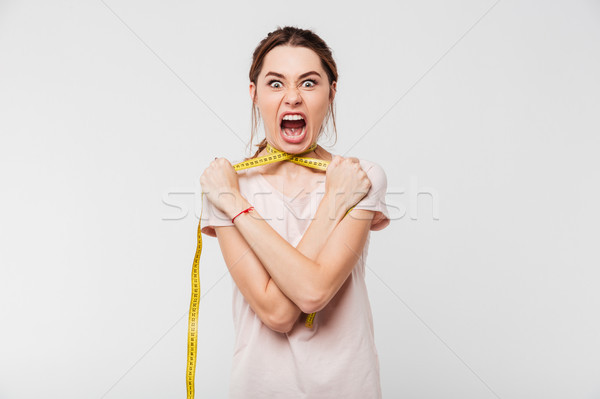 Portrait of a young screaming girl strangling herself Stock photo © deandrobot
