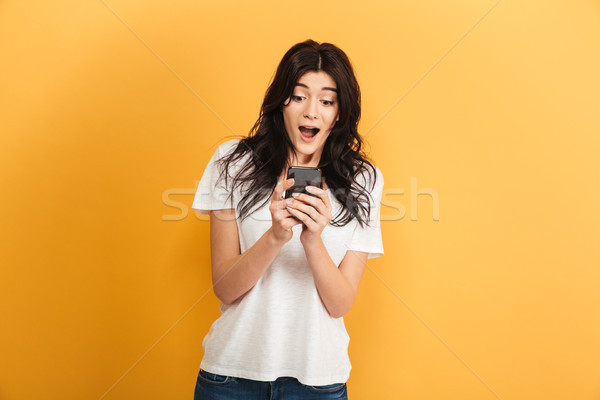 Emotional cute young pretty woman using mobile phone looking aside. Stock photo © deandrobot