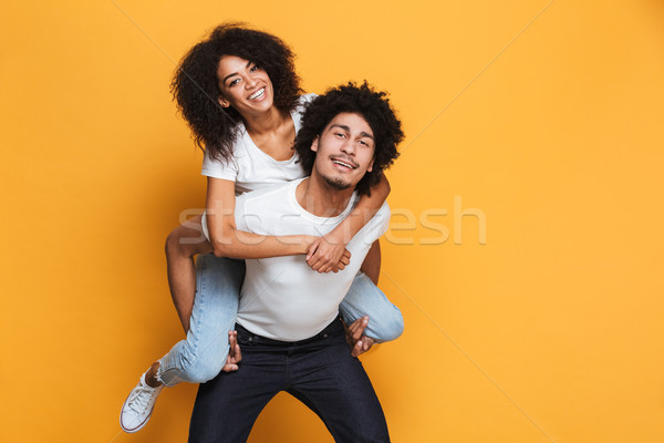 Portrait of an african young man carrying girlfriend Stock photo © deandrobot