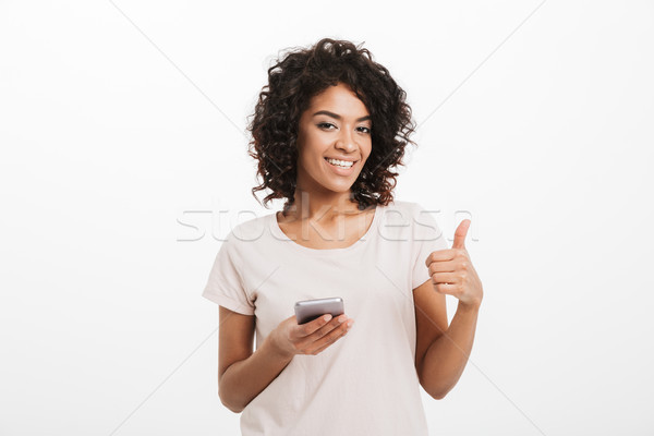 Joyous american woman with afro hairstyle and big smile chatting Stock photo © deandrobot