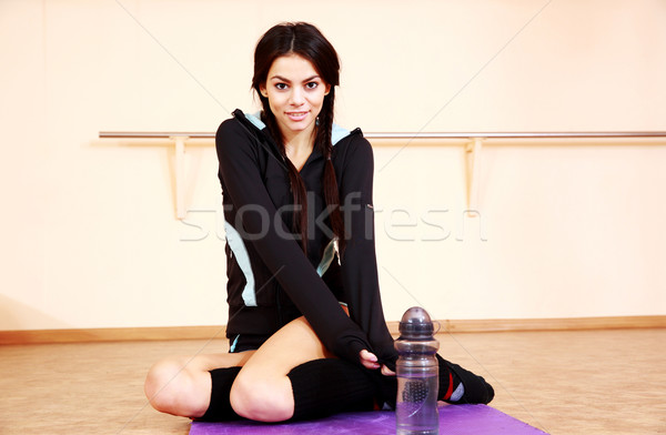Young smiling fit woman sitting on the floor at gym Stock photo © deandrobot