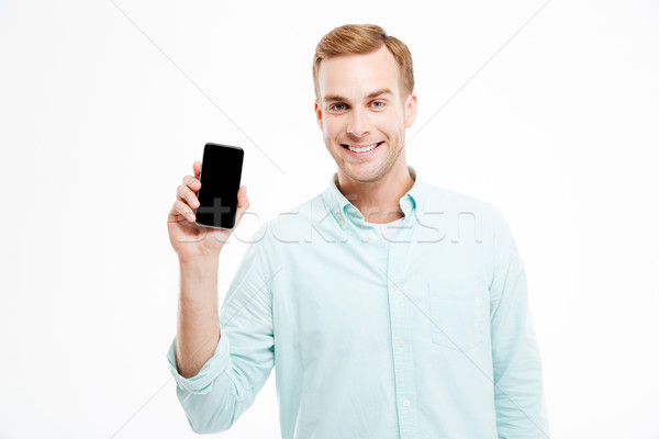 Smiling attractive young businessman holding blank screen smartphone Stock photo © deandrobot