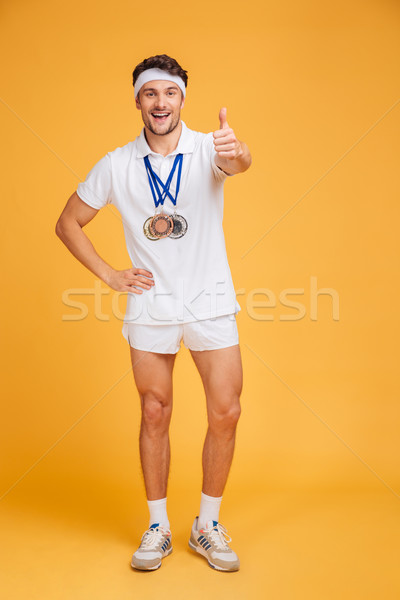 Happy spotrsman with three medals standing and showing thumbs up Stock photo © deandrobot