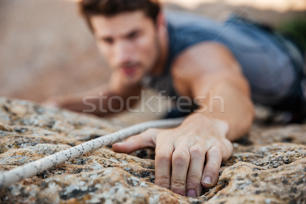 Man reaching for a grip while he rock climbs Stock photo © deandrobot