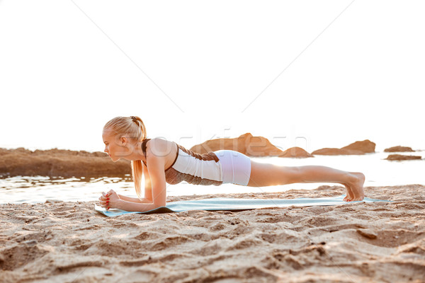 Portrait of a blonde woman doing planking on yoga mat Stock photo © deandrobot