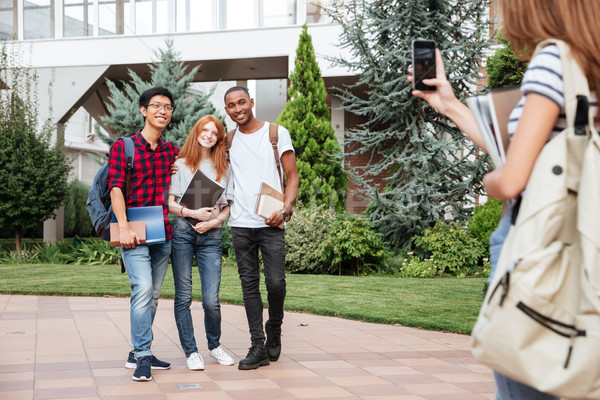 Woman student taking photos of her smiling friends in campus Stock photo © deandrobot