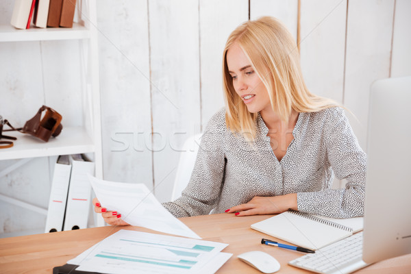Businesswoman sitting at her working place with papers and pc Stock photo © deandrobot