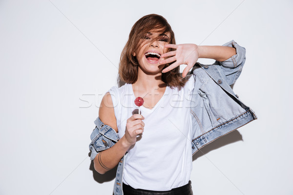 Young happy lady eating candy. Stock photo © deandrobot