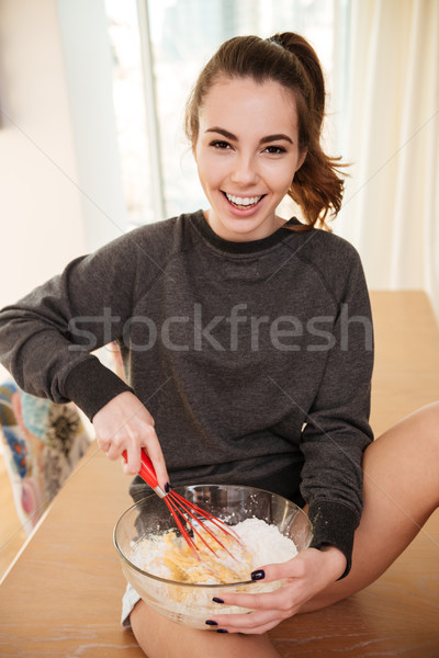 Smiling cute girl blending eggs and flour in glass bowl Stock photo © deandrobot