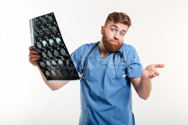 Portrait of a frustrated helpful medical doctor holding CT scan Stock photo © deandrobot