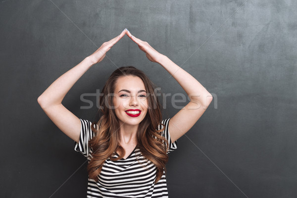 Smiling woman holding hands overhead Stock photo © deandrobot