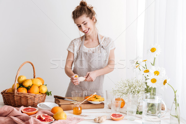 Lady standing indoors and squeezes out juice of a citruses Stock photo © deandrobot