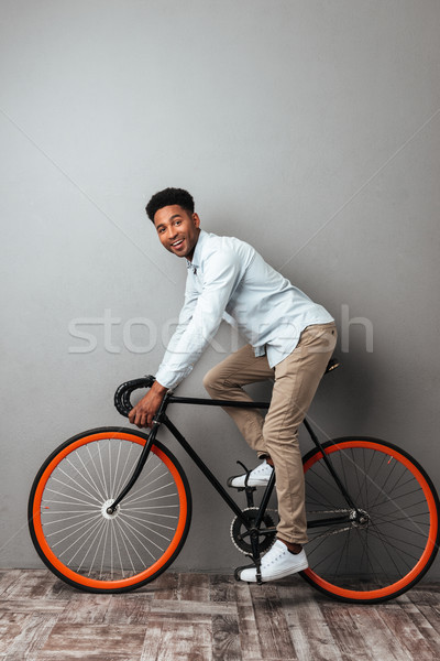 African man standing over grey wall with bicycle. Stock photo © deandrobot