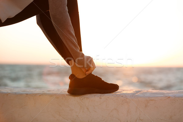 Cropped photo of sport woman tying shoelace at the seaside Stock photo © deandrobot