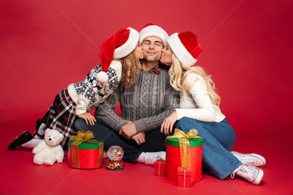 Cute cheerful young family wearing christmas hats sitting isolated Stock photo © deandrobot