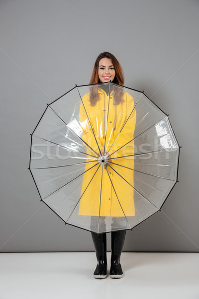Full length portrait of a cheerful girl dressed in raincoat Stock photo © deandrobot