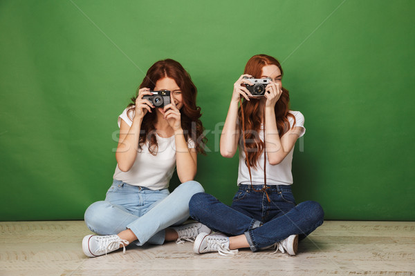 Photo of two redhead girls 20s sitting on floor with legs crosse Stock photo © deandrobot