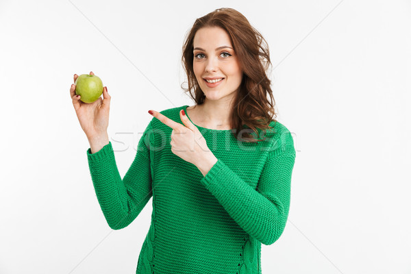Portrait of a smiling young woman pointing finger at apple Stock photo © deandrobot