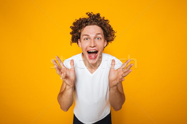 Portrait of positive guy with curly brown hair screaming with ra Stock photo © deandrobot