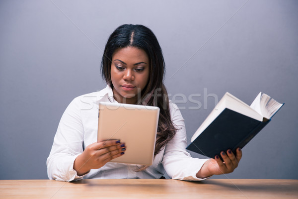 Businesswoman choosing between e-book or paper book Stock photo © deandrobot