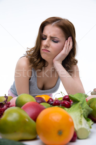 Stock photo: Portrait of a dissatisfied woman sitting at the table with fruits