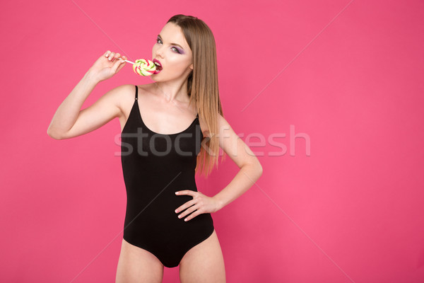 Pretty girl with red lips tasting candy Stock photo © deandrobot