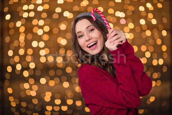 Cheerful attractive young woman holding sweet candy cane and smiling  Stock photo © deandrobot