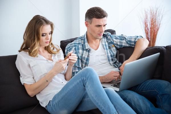 Belo casal usando laptop separadamente sessão Foto stock © deandrobot