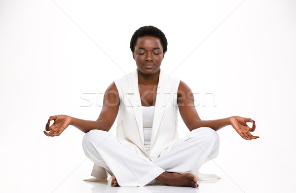 Relaxed beautiful african woman sitting and meditating in yoga pose Stock photo © deandrobot