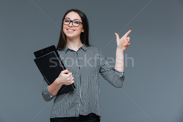 Happy businesswoman pointing finger away Stock photo © deandrobot