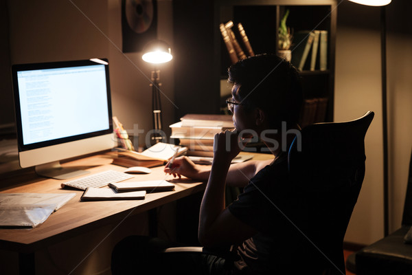 Thoughtful man studying using computer in dark room at home Stock photo © deandrobot