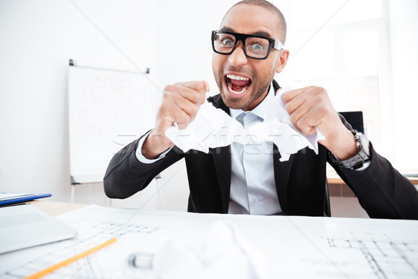 Angry businessman tearing up a document in office Stock photo © deandrobot