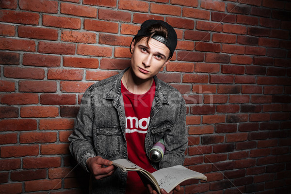 Graffiti man holding sketchbook isolated over red brick wall Stock photo © deandrobot