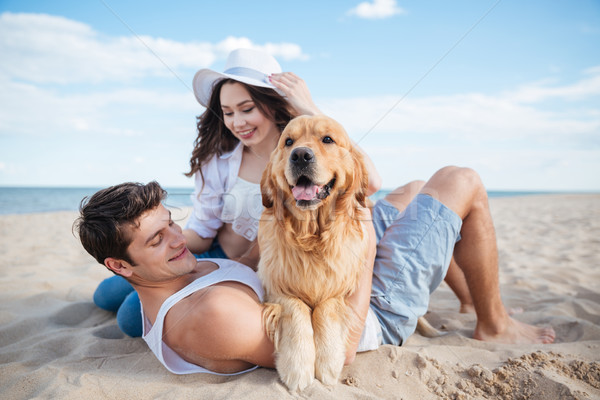Couple in love playing with their dog on the beach Stock photo © deandrobot