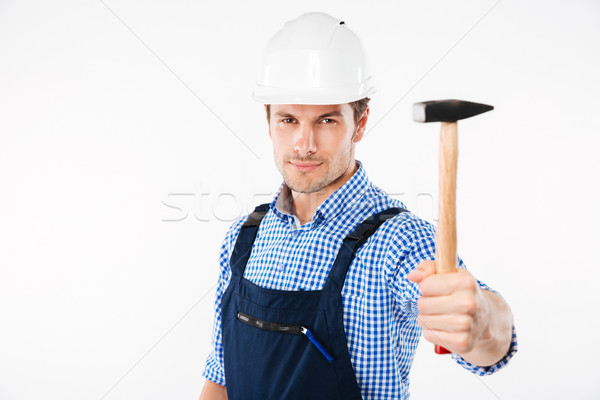 Happy young builder in helmet standing and holding hammer Stock photo © deandrobot