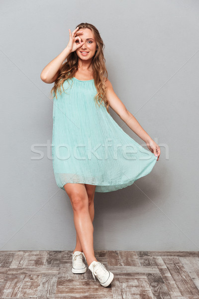 Smiling beautiful young woman looking at camera through fingers Stock photo © deandrobot