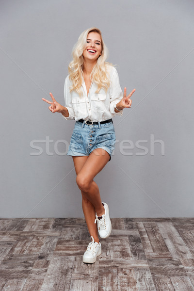 Full length portrait of a cheerful woman showing peace sign Stock photo © deandrobot
