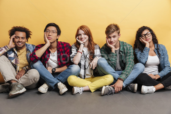 Groupe souriant jeunes séance jambes croisées [[stock_photo]] © deandrobot