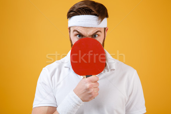 Emotional young sportsman holding racket for tennis covering mouth. Stock photo © deandrobot