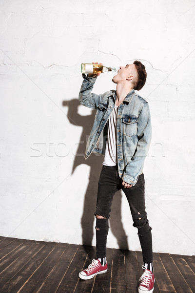 Handsome man standing on floor drinking alcohol Stock photo © deandrobot