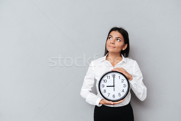 Stock photo: Business woman holding clock and looking up