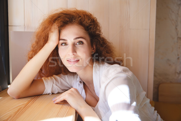 Portrait of a lovely redhead woman leaning on windowsill indoors Stock photo © deandrobot