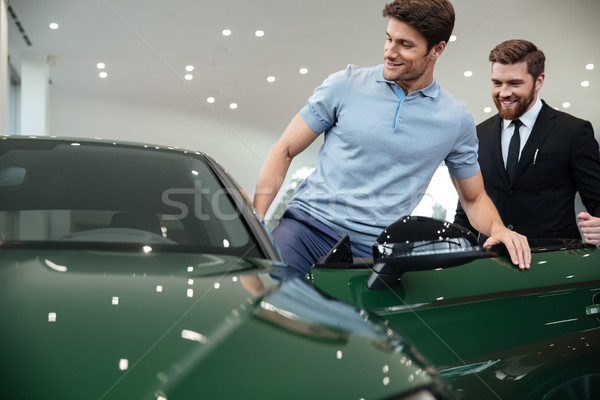 Young male customer getting inside his new car Stock photo © deandrobot