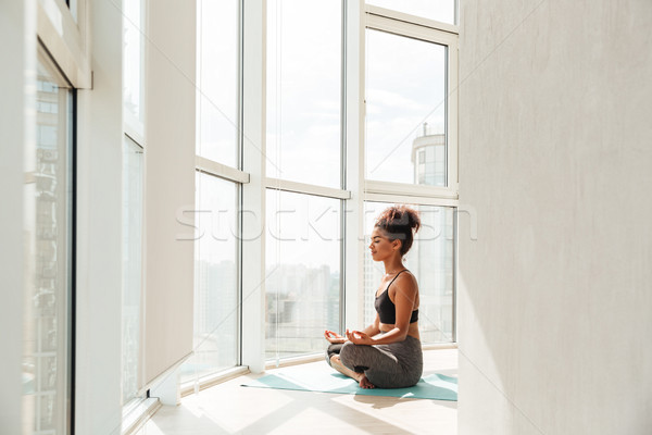 Young lady sitting in lotus pose and looking camera Stock photo © deandrobot