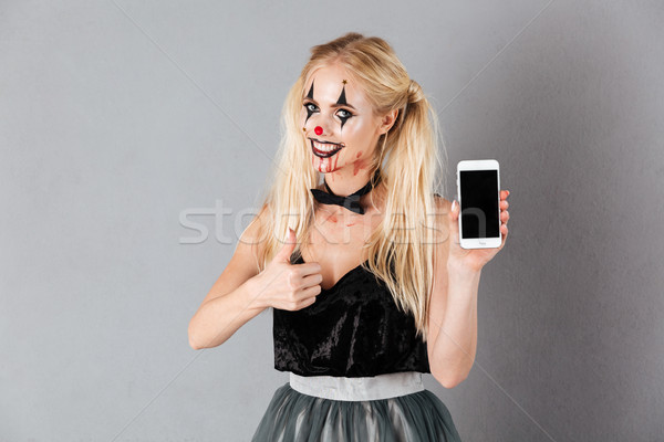 Smiling blonde woman in halloween make up showing smartphone Stock photo © deandrobot