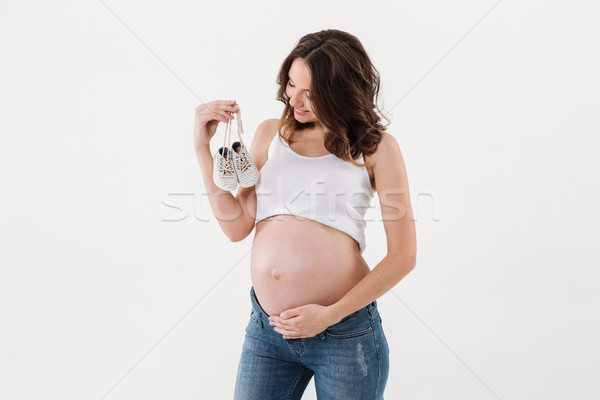 Happy pregnant woman holding little baby shoes. Stock photo © deandrobot