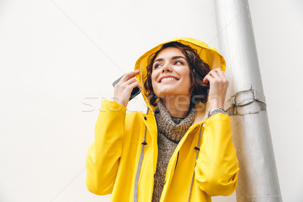 Close up picture of stylish female in yellow coat wearing hood o Stock photo © deandrobot