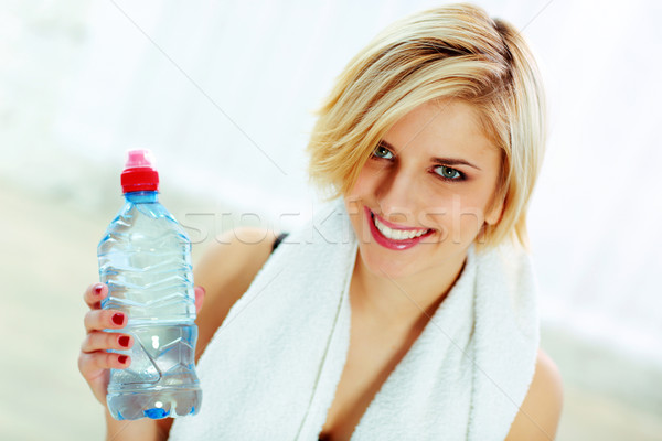 Closeup portrait of a young cheerful fit woman with bottle of water Stock photo © deandrobot