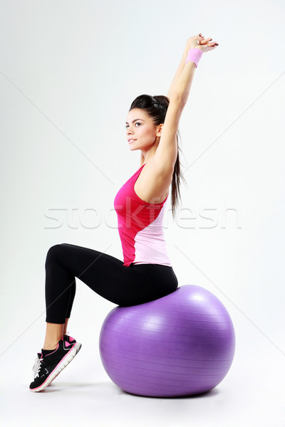 Young thoughtful sport woman stretching on fitball on gray background Stock photo © deandrobot
