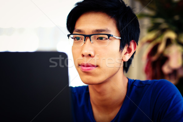 Serious asian man working on the laptop Stock photo © deandrobot